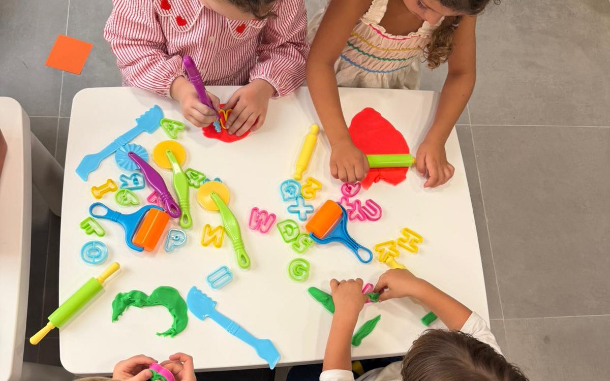 Niños en un taller de KIDO PLAY modelando plastilina con letras y moldes sobre la mesa